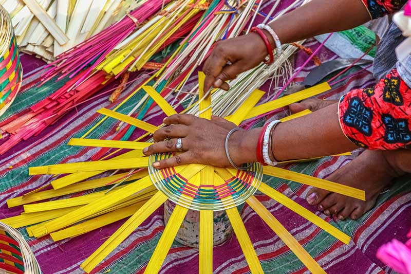 femme indienne fabrique un panier avec des lanières colorées